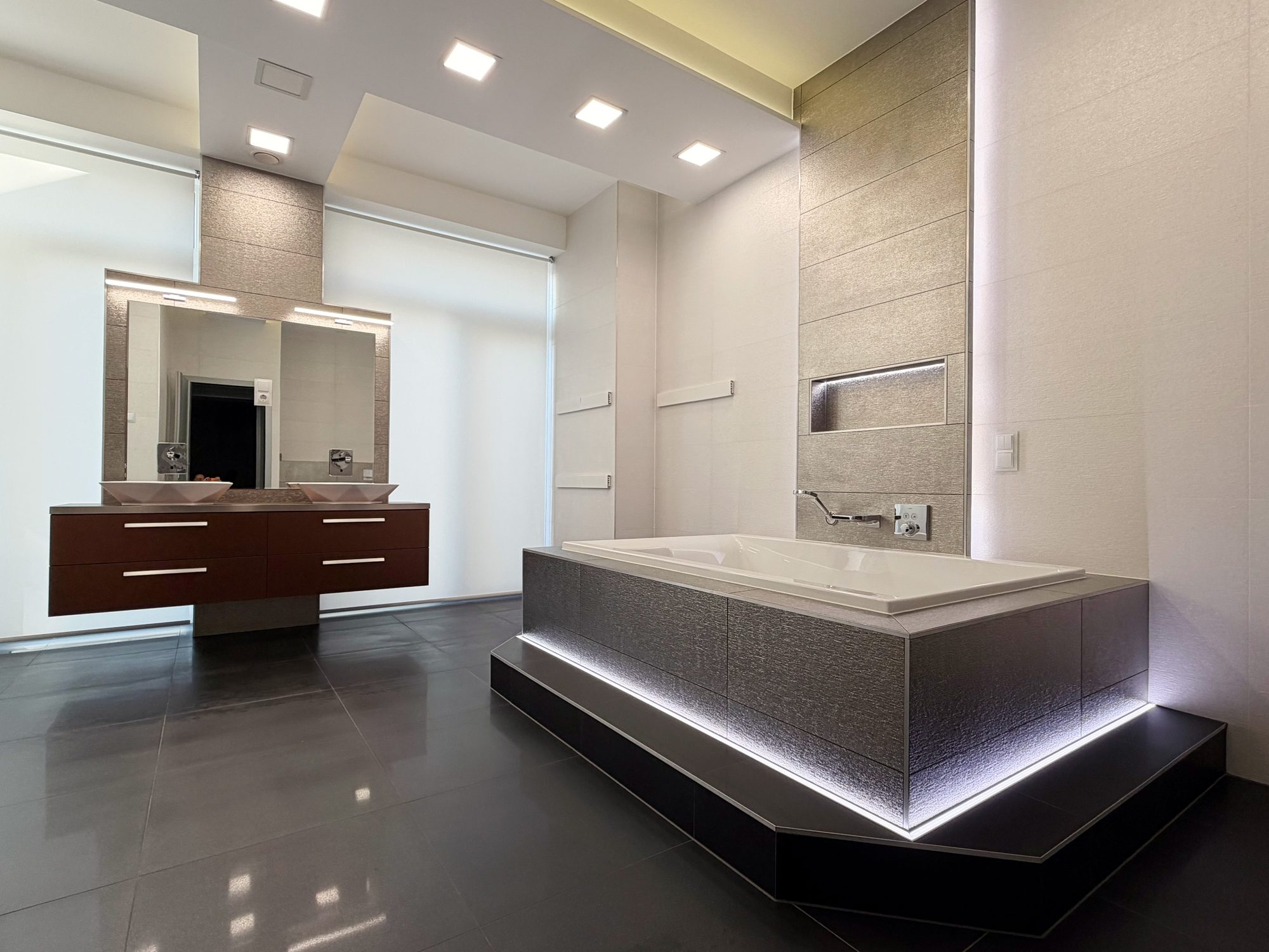 Bathroom with a raised, underlit bathtub and double washbasin