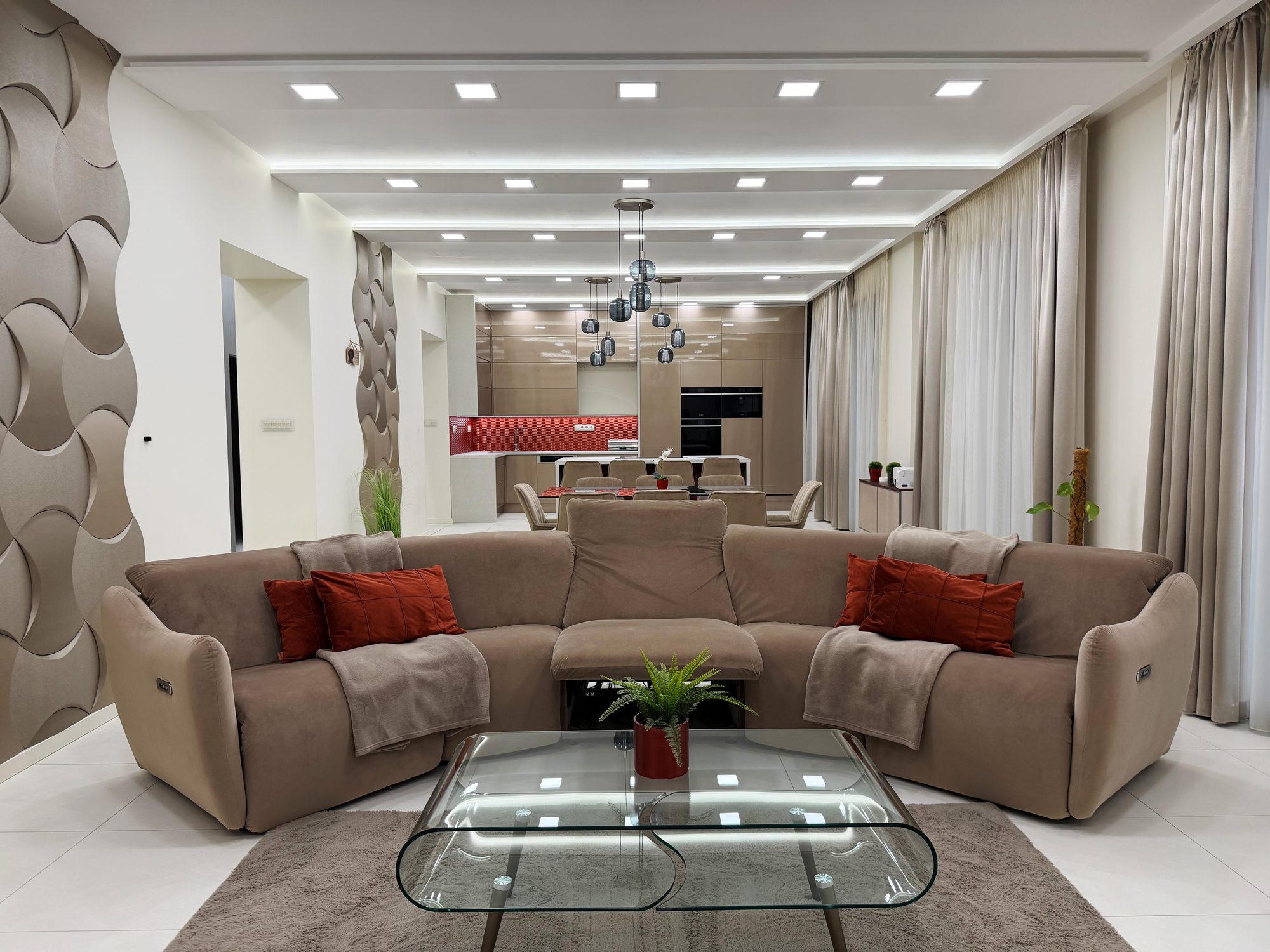 Open-plan living room with a curved sofa, the dining area and kitchen beyond