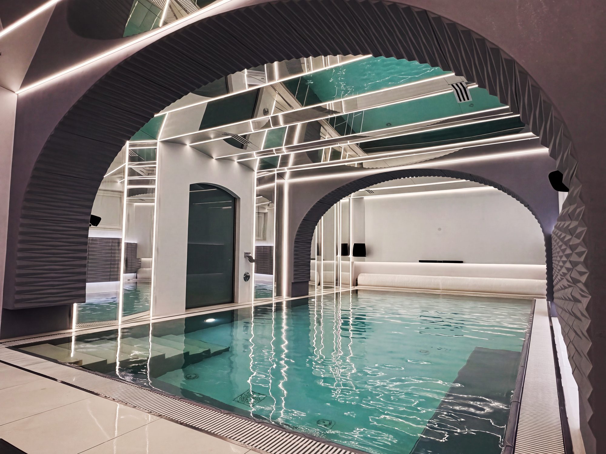 Heated indoor pool under arches, with mirrored ceiling and lines of light